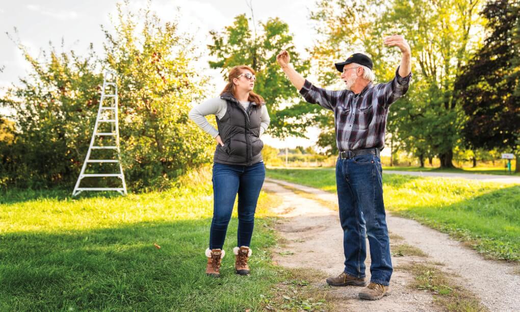 Two people talk in an orchard